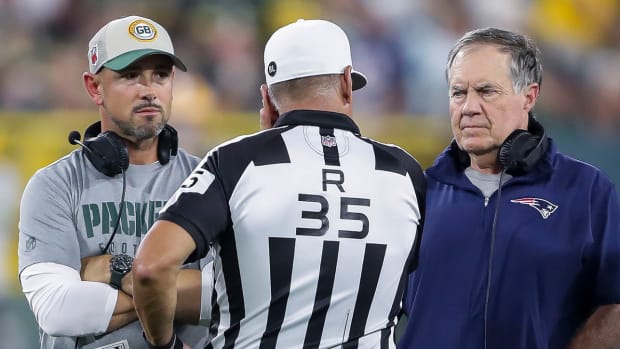 Packers coach Matt LaFleur and Patriots coach Bill Belichick talk with referee John Hussey (35) during their football game at Lambeau Field.